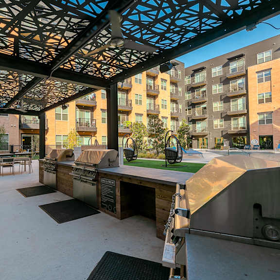 a patio area with a grill and picnic tables.
