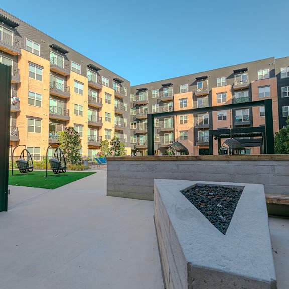 a modern courtyard with a bench and a table surrounded by buildings.