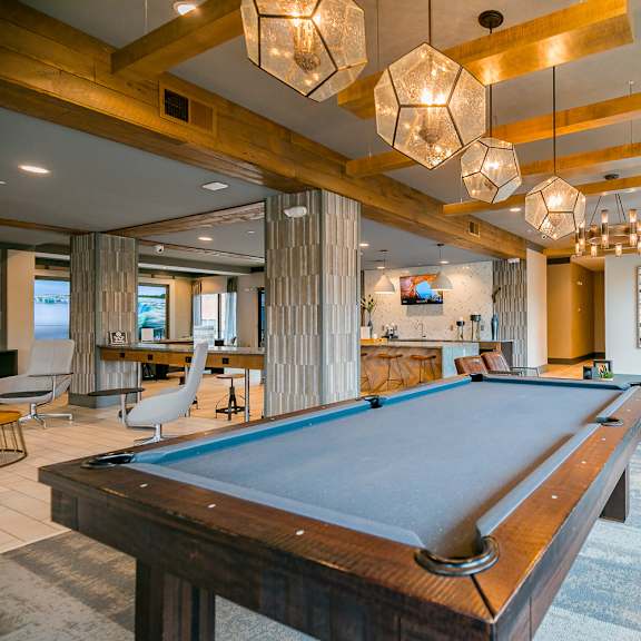 a pool table is in the middle of a room with a wooden ceiling and a bench.
