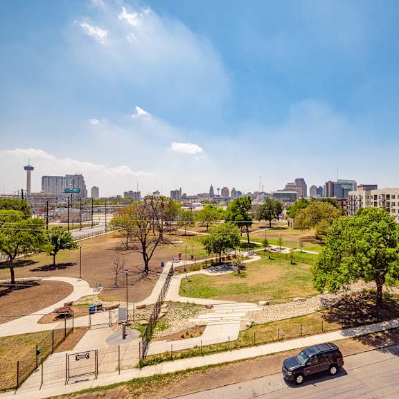 a city street with cars and a green park area.