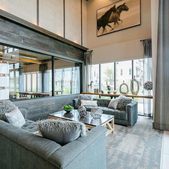 a living room with a grey couch and a painting of a horse on the wall.
