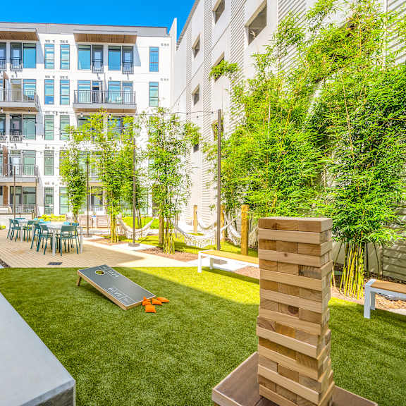a backyard with a trampoline, picnic table and chairs and an apartment building in the