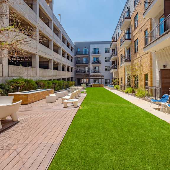 a sunny day at a modern apartment complex with a long wooden deck and lounge chairs.