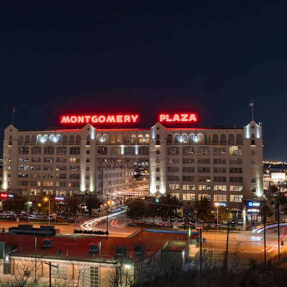 montgomery plaza is a large building with a red neon sign on top.