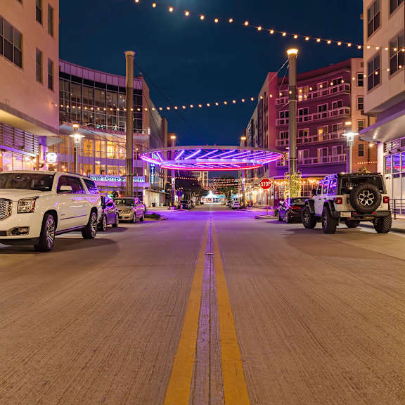 a street with cars parked on the side and buildings on either side.