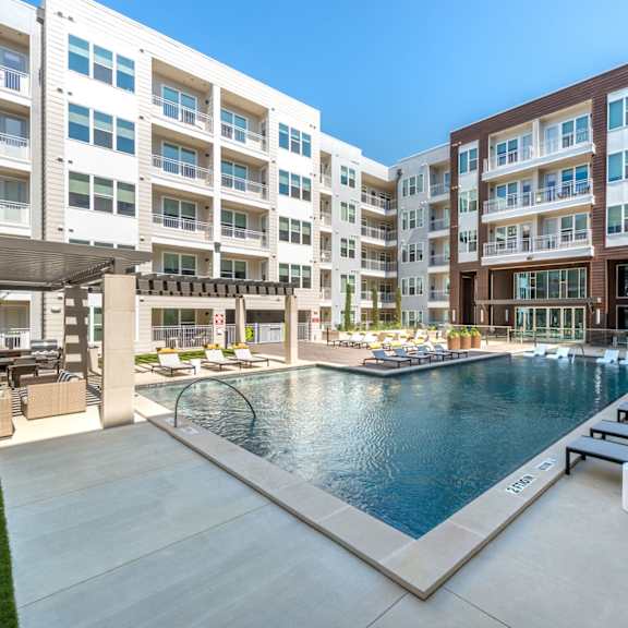 a large swimming pool surrounded by lounge chairs and buildings.