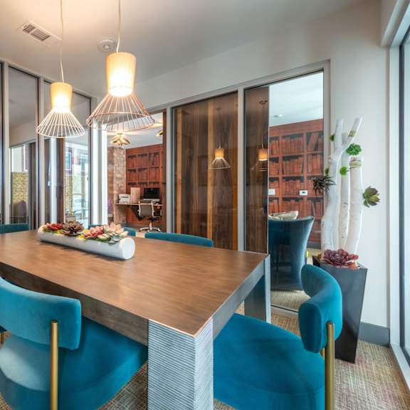 a modern dining room with a wooden table and blue chairs.
