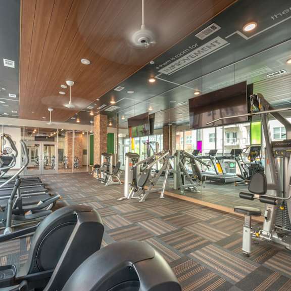 a gym with treadmills, elliptical machines, and other exercise equipment.