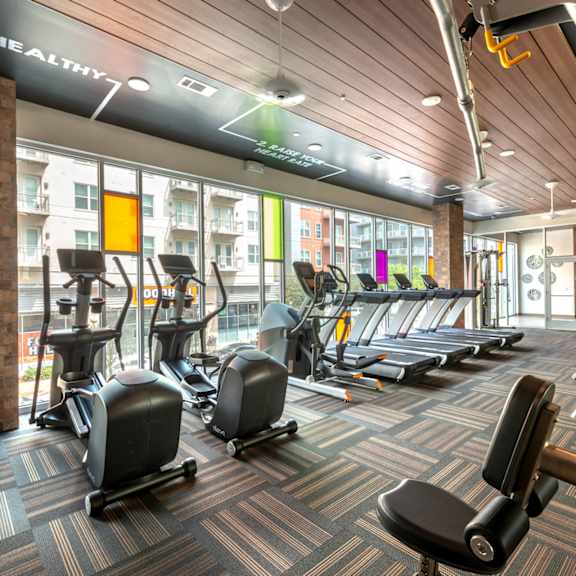 a gym with a variety of equipment including treadmills, stationary bikes, and weight machines.