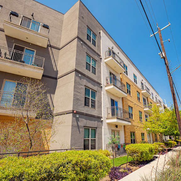 a row of modern apartment buildings with balconies and greenery in front.