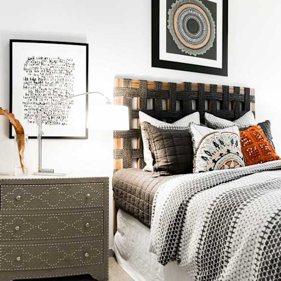 a bedroom with a bed, nightstand, and artwork on the wall.