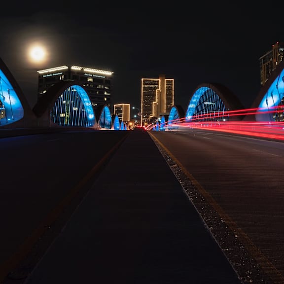 a long exposure shot of a bridge at night with light trails from moving vehicles.