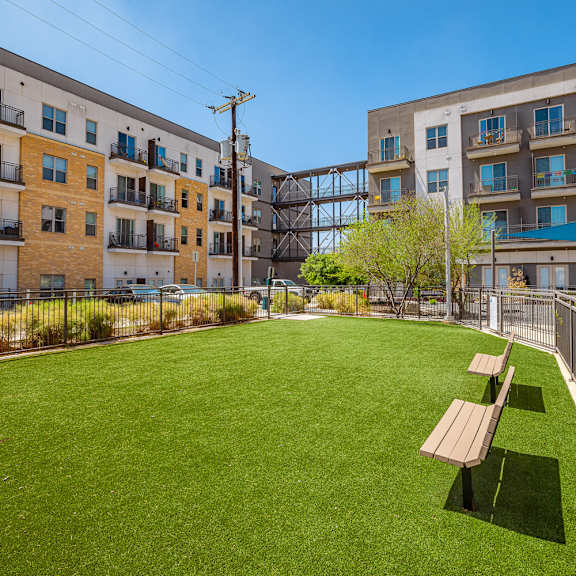 a grassy area with benches in front of apartment buildings.