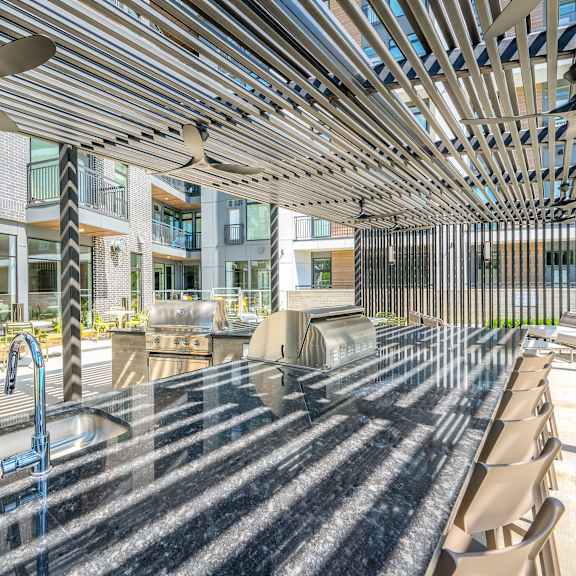 a communal table with chairs and a grill in front of an apartment building