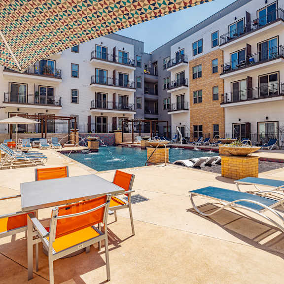 a patio with a table and chairs is surrounded by buildings.