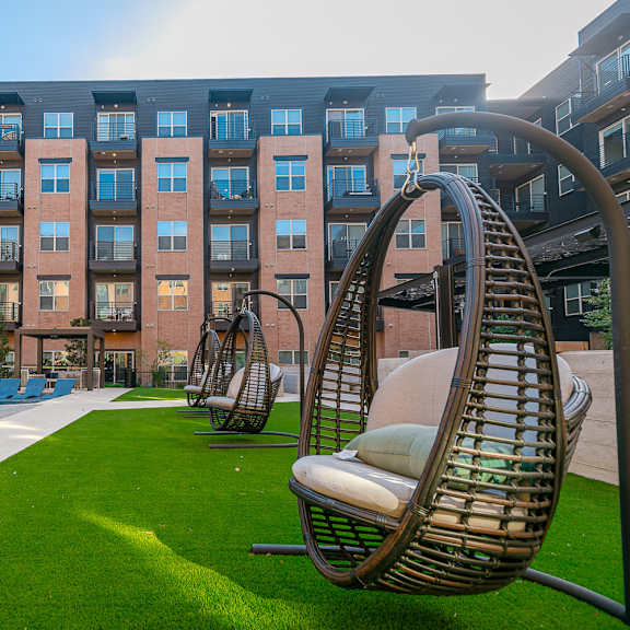 a modern building with a grassy area in front and several chairs.