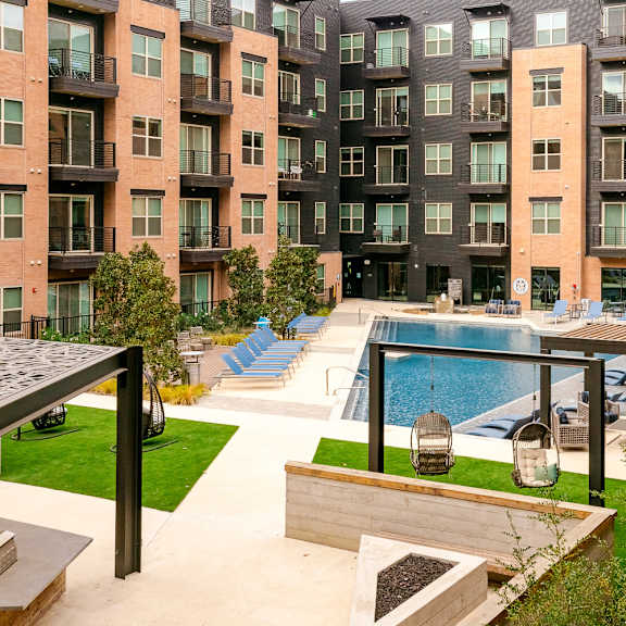 a view of a pool and patio area in front of apartment buildings.