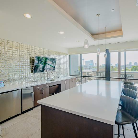 a kitchen with a long white counter and a view of the city.
