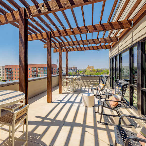 a wooden pergola over a patio with a table and chairs.