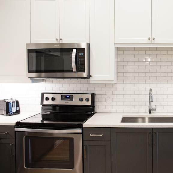 a modern kitchen with a black stove and white cabinets.