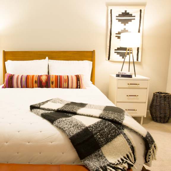 a bed with a white comforter and a black and white striped blanket.