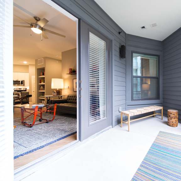 a balcony with a blue rug and a wooden bench.