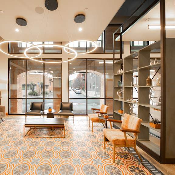 a modern waiting room with a patterned carpet and a glass wall.
