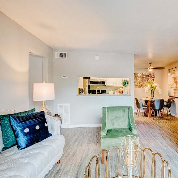 a living room with a white couch, green chair, and a painting on the wall.
