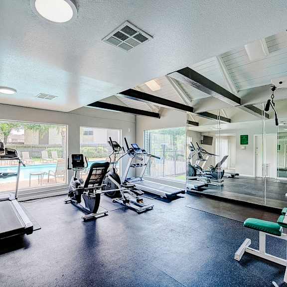 a spacious gym with a variety of equipment including treadmills, weights, and exercise machines.