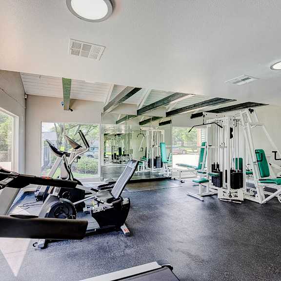 a gym with treadmills, elliptical machines, and other exercise equipment.
