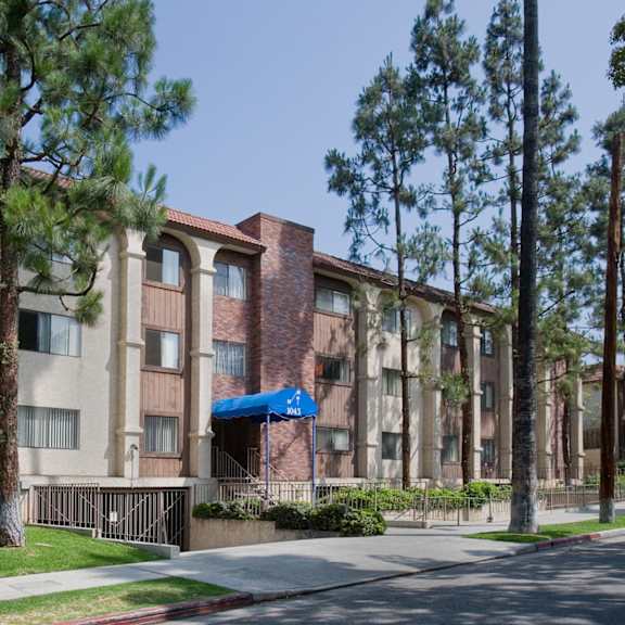a building with a blue awning is surrounded by trees.