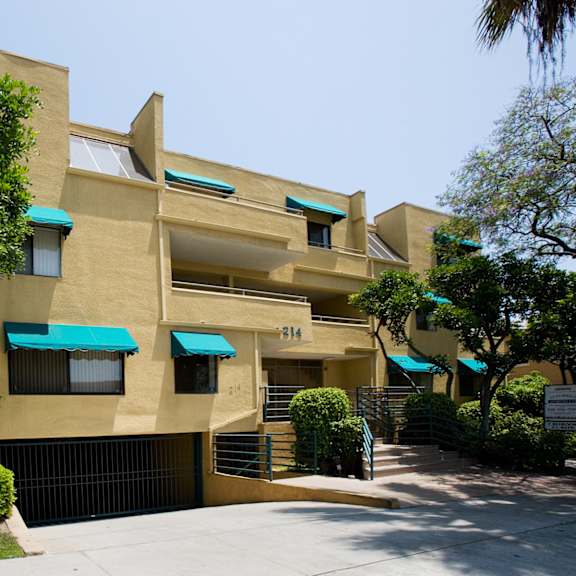 a modern building with a beige facade and blue awnings.