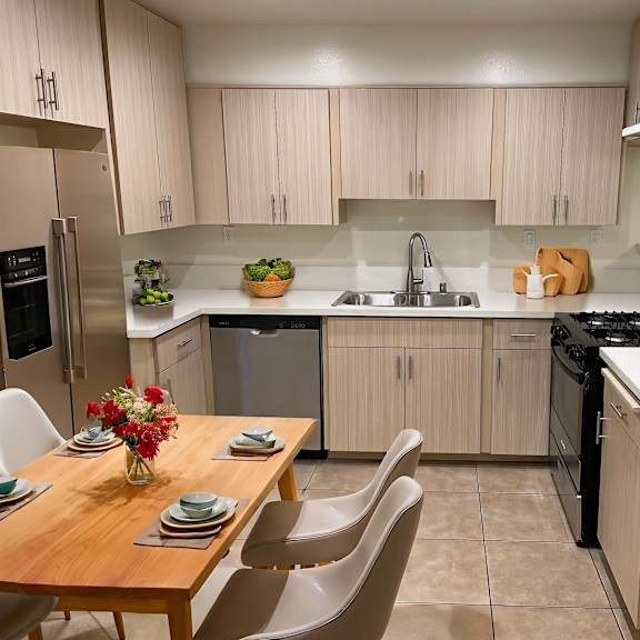 a kitchen with a table set for four with a bowl of fruit on it.