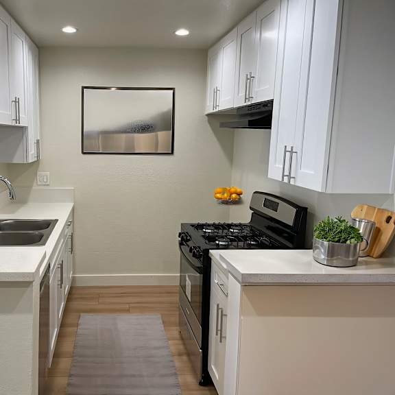 a modern kitchen with white cabinets and a black stove top.