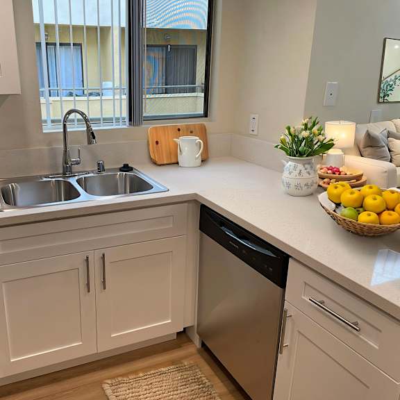a kitchen with a sink, stove, and a bowl of fruit on the counter.