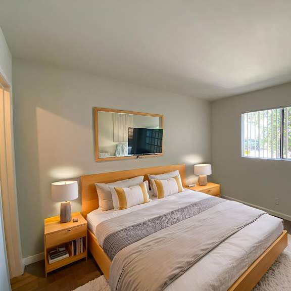 a bedroom with a large bed, a chair, and a potted plant.