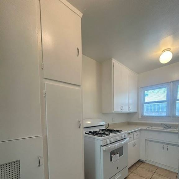 a kitchen with a white refrigerator, stove, and cabinets.
