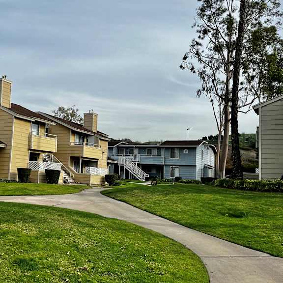 a row of houses on a grassy hill with a cloudy sky in the background