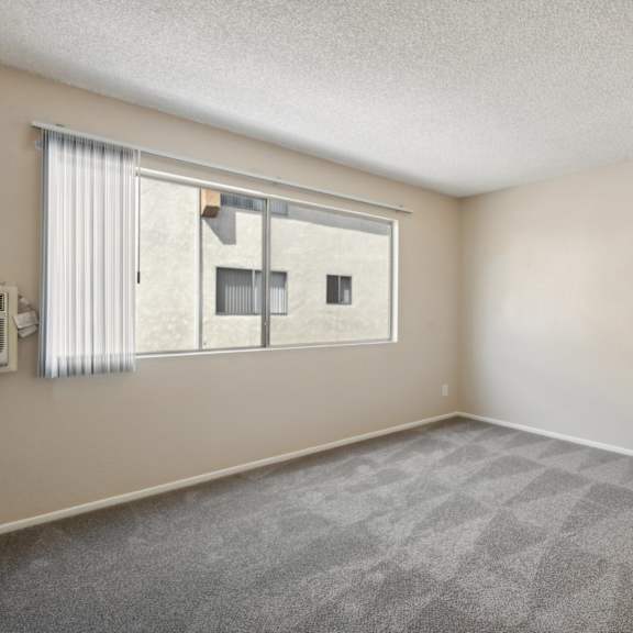 the spacious living room of an apartment with a large window