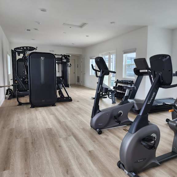 a spacious gym with a variety of cardio equipment.