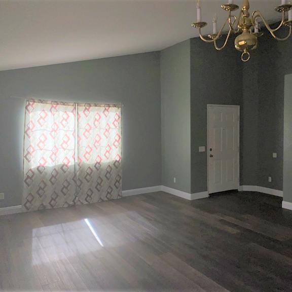an empty room with a chandelier and a window with a curtain
