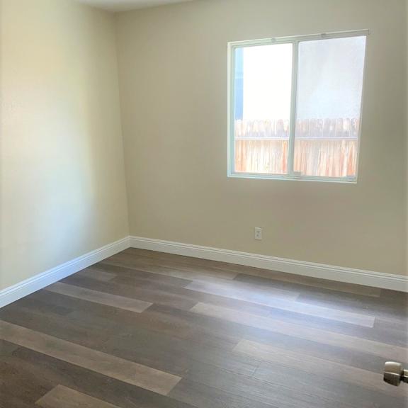 an empty room with a window and wooden floors