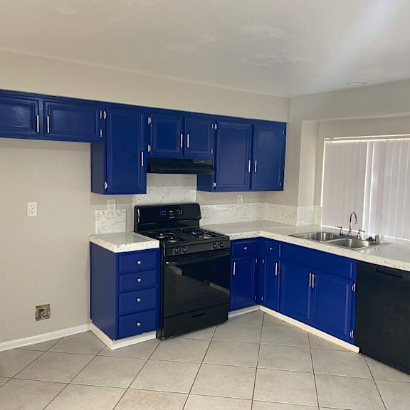 a kitchen with blue cabinets and a stove and a sink