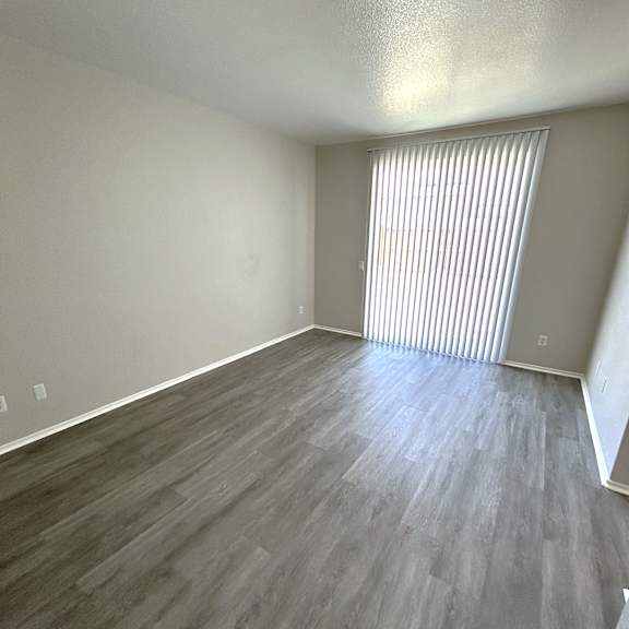 a room with wooden flooring and a window with blinds.