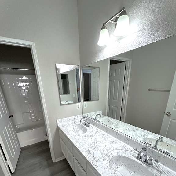 a bathroom with a marble countertop and a large mirror.