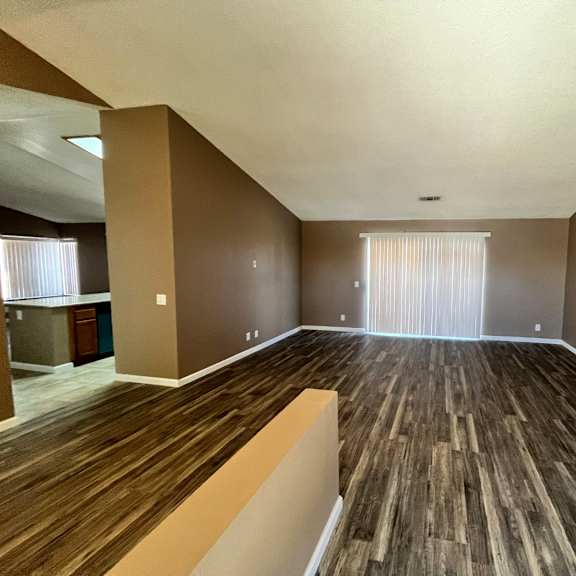 a room with wooden flooring and a window with blinds.