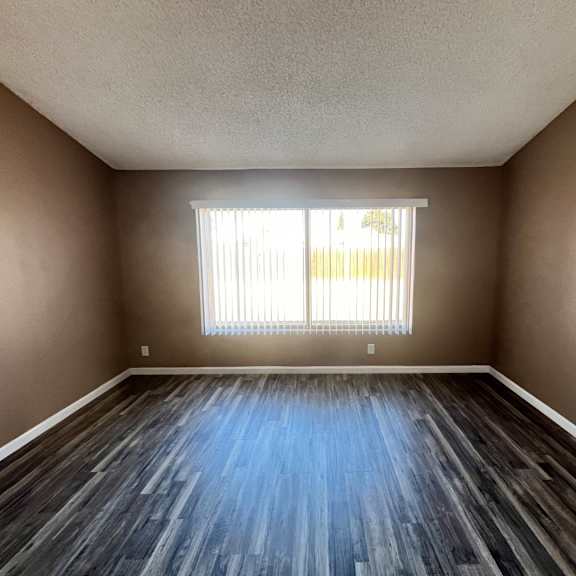 a room with wooden flooring and a window with blinds.