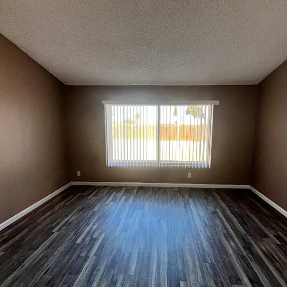 a room with wooden flooring and a window with blinds.