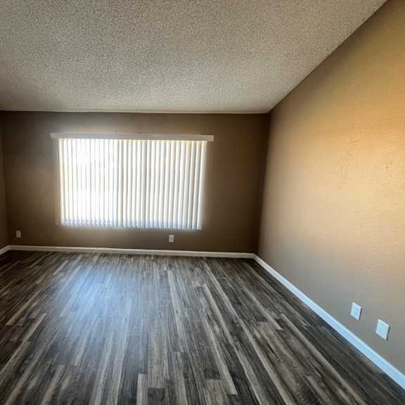 a room with wooden flooring and a window with blinds.