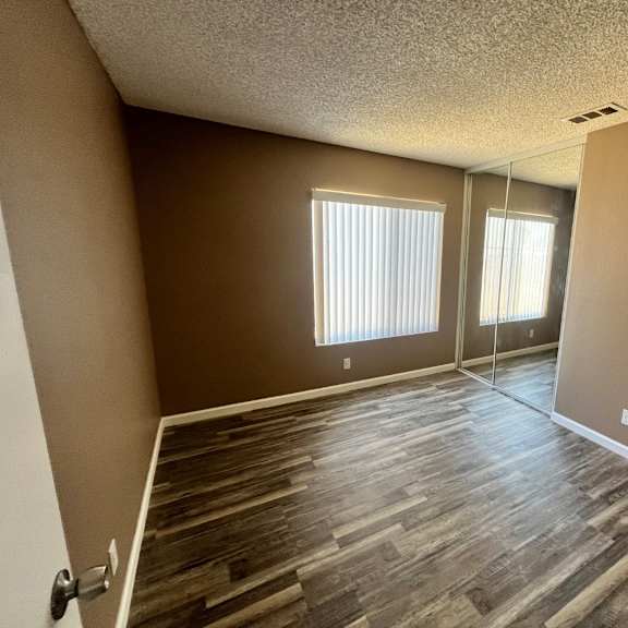 a room with wooden flooring and two windows.